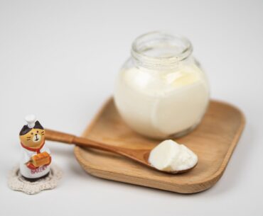 jar with delicious plain yogurt and wooden spoon on saucer