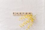 easter text on gray surface beside yellow flowers